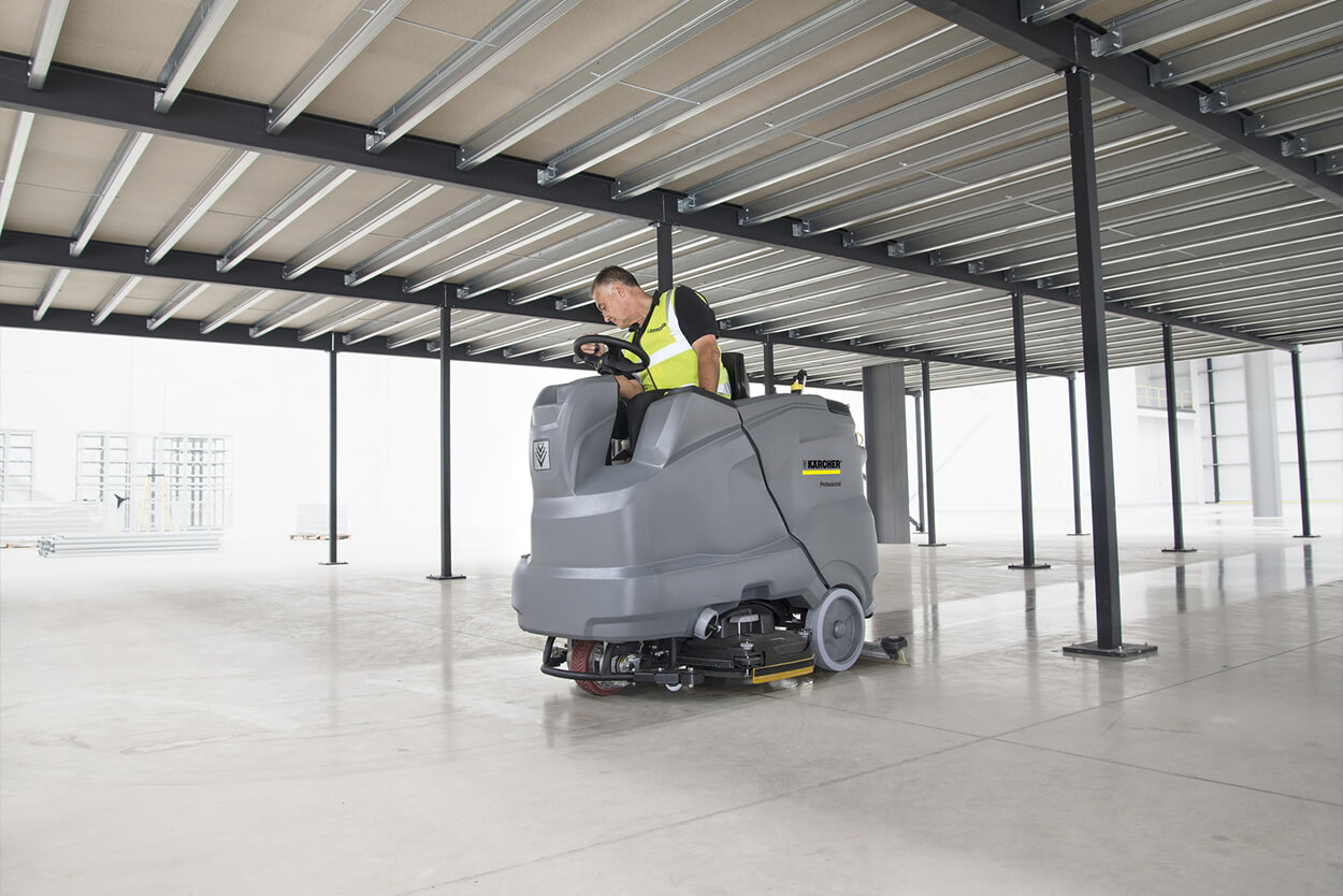 Man riding B 150 R Ride-On Scrubber Dryer in empty warehouse
