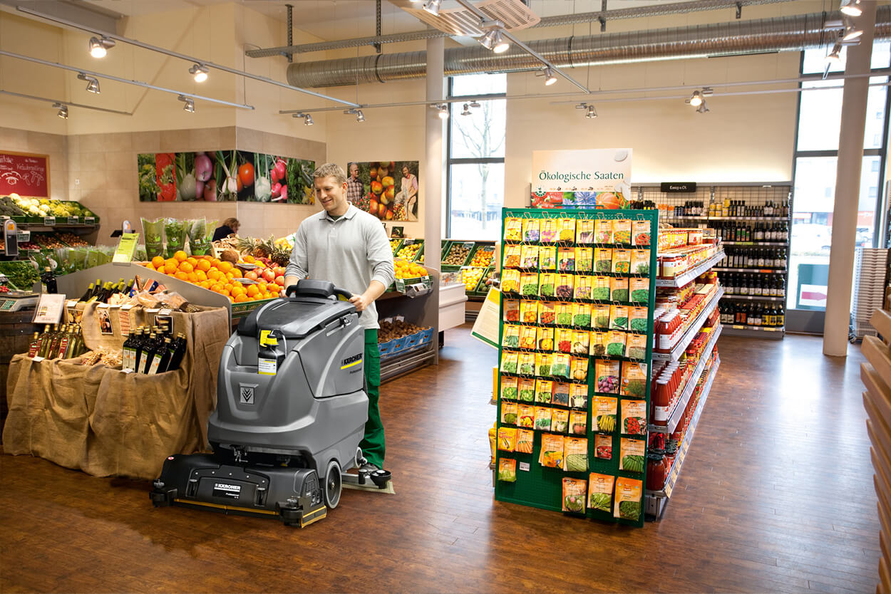 Man operating B 80 W Scrubber cleaning machine in empty shopping store