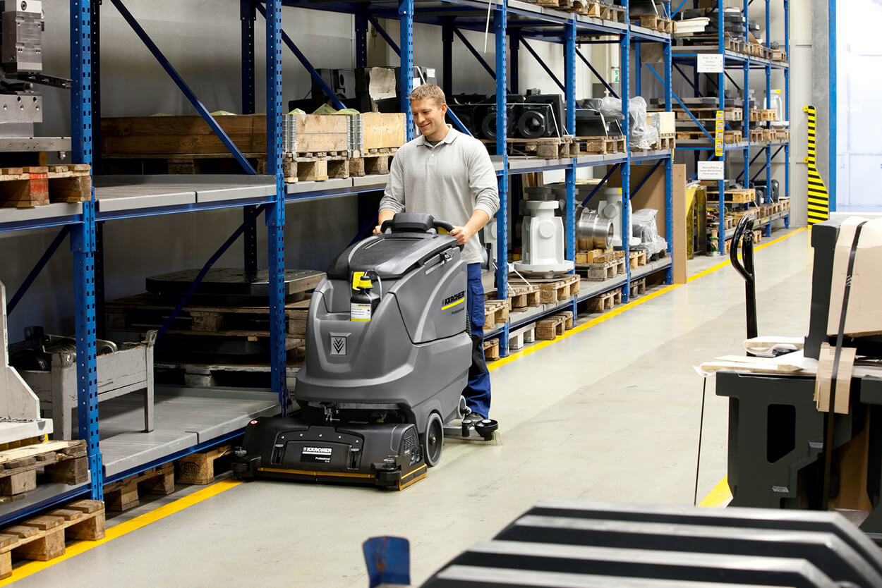 Man operating B 80 W cleaning machine at empty warehouse