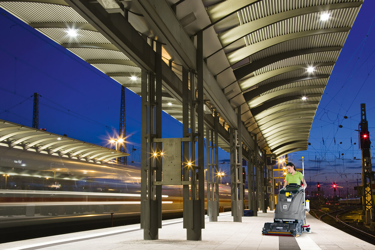 Women operating B 60 W scrubber dryer cleaning machine at empty rail train station