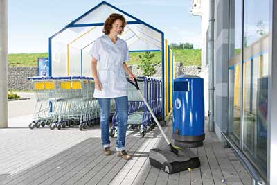 Handheld floor sweeper cleaning a shop entrance